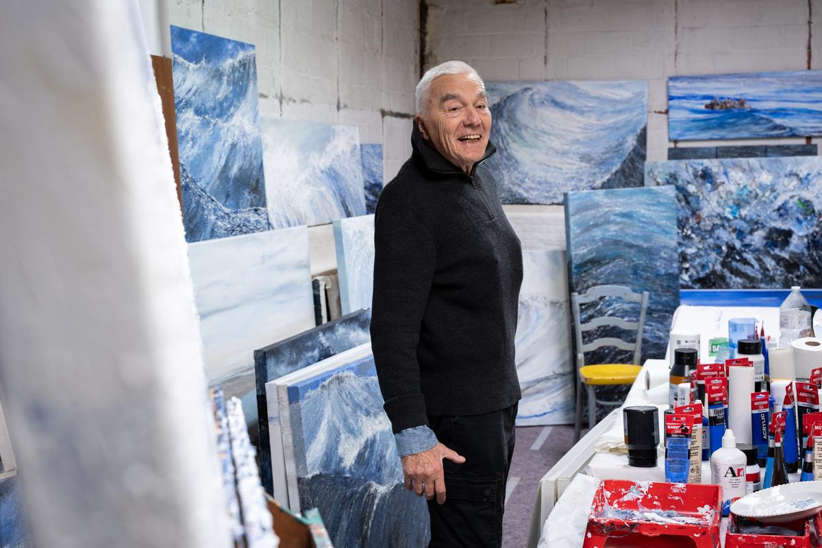 Kunstenaar Jean-Pierre Zinjé bij zijn kunstwerken over de zee